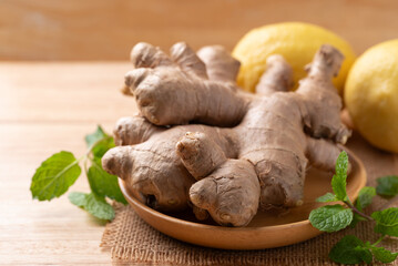 Fresh ginger, lemon and mint leaf on wooden background