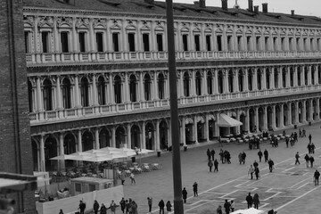 Square with people. Historic arcade building on Piazza San Marco in Venice, Italy. Elegant Renaissance architecture with rows of arches, columns, and symmetry. 