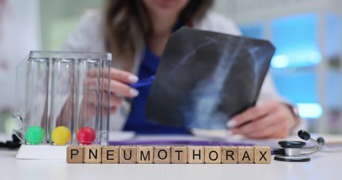 Wooden blocks spell word Pneumothorax near spirometer and x-ray film. Woman pulmonologist studies lung image writing notes about collapsed lung