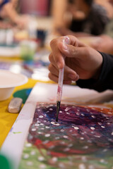 Main d'un enfant tenant un pinceau lors d'un atelier de peinture