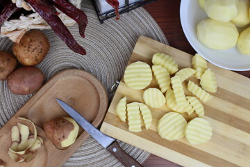 On the table, the process of peeling and preparing potatoes for dinner is taking place.