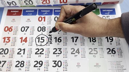 Man marking the date on calendar for reminder of meeting and appointment. Man making his checklist on calendar. Young man marking dates on calendar for events schedules and appointment.