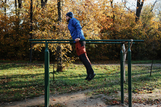 A man exercises on parallel bars in a park. The moment reflects discipline and committed outdoor training.