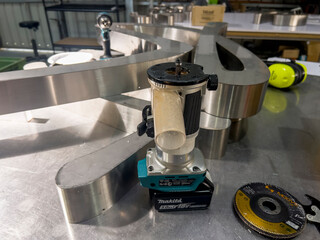 Makita trim router standing vertically on stainless steel letter structure