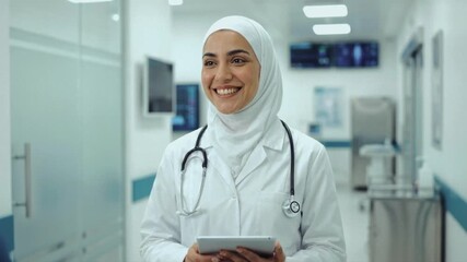 Muslim female doctor walking in a hospital corridor holding a digital tablet. Professional woman in hijab and lab coat smiling at a colleague. Modern healthcare and medical technology concept - Powered by Adobe