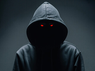 Mysterious figure in hoodie with glowing red eyes evokes suspense and intrigue, perfect for thriller or crime themes, adding a touch of the unknown