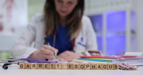 Term Barrett Esophagus appears on wooden blocks on clinical desk near pills. Woman gastroenterologist reads report adjusting patient reflux plan