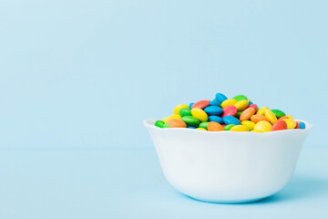 Multicolored candies in a bowl on a colored background. birthday and holiday concept. Top view with copy space