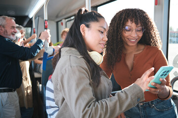 Women friends using smartphone commuting on public transport