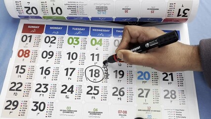 Man marking the date on calendar for reminder of meeting and appointment. Man making his checklist on calendar. Young man marking dates on calendar for events schedules and appointment.