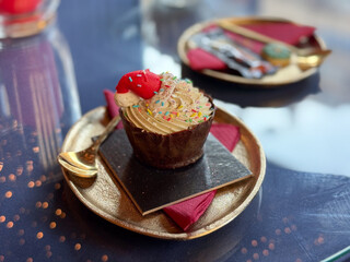 Festive cupcake served on a golden plate in a holiday cafe. Sweet celebration, joyful tradition and warm Christmas storytelling creating cozy seasonal mood and delightful winter atmosphere