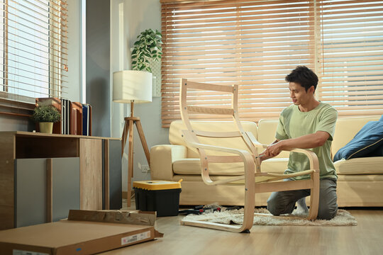 A man assembling new rocking armchair at home with screwdriver, DIY home improvement - Powered by Adobe