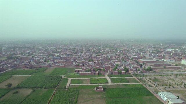 Multan, Pakistan - 06 September 2025: Aerial view of green fields contrasting with buildings, showcasing the rural-urban mix in a single picturesque landscape.