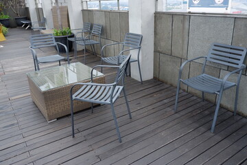 Outdoor seating area with modern metal chairs and a wicker coffee table on a dark wooden deck, perfect for a balcony or patio setting
