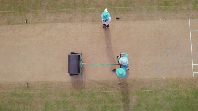 Multan, Pakistan - 06 September 2025: Aerial view of two groundsmen meticulously rolling the cricket pitch, creating a smooth surface for the upcoming match.
