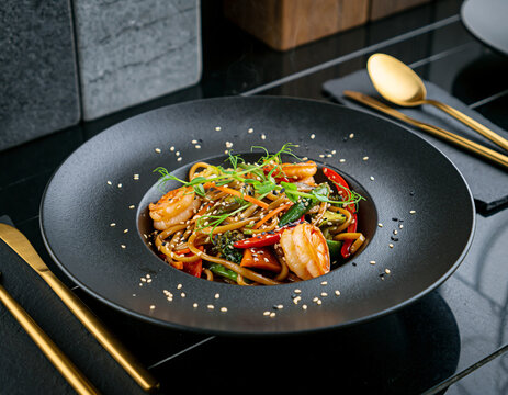 Shrimp Stir Fry Udon Noodles with Vegetables on Dark Restaurant Plate