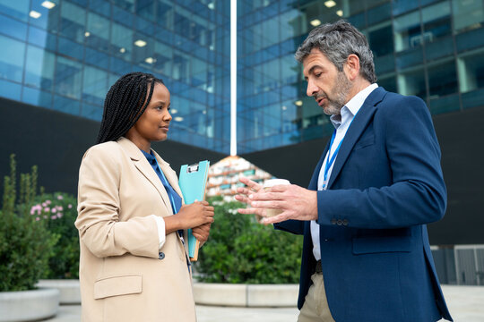 Diverse business people discussing outdoors in front of office building