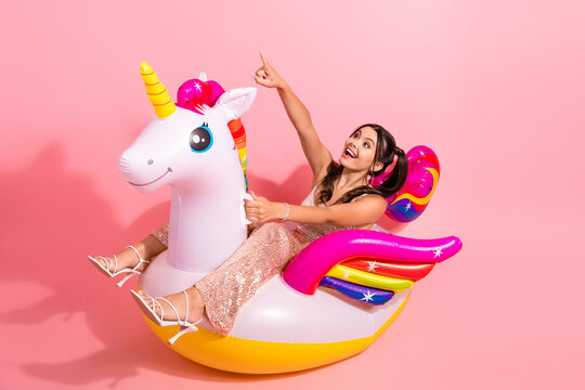 Fototapeta Young woman glittery pink dress rides colorful inflatable unicorn soft pink background festive lifestyle advertising campaigns holiday promotions
