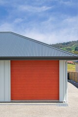 Closeup of a red garage door on a newly constructed home in an Australian suburban housing development; a symbol of the housing affordability and construction crisis.