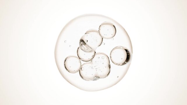 Macro of drops of liquid moving inside bubbles. Skin care serum droplets uniting into one. Cosmetics moisturizer fluid concept. Looping animation