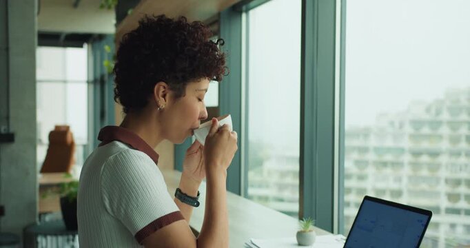 black woman freelance designer sipping coffee at window
