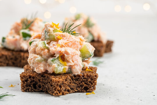 Sourdough bread topped with salmon pate served on a light background