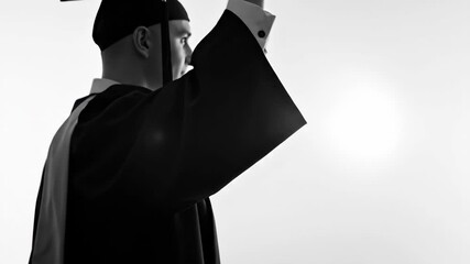 Man celebrates graduation day holding diploma. A graduate student in cap and gown rejoices success after receiving higher education.