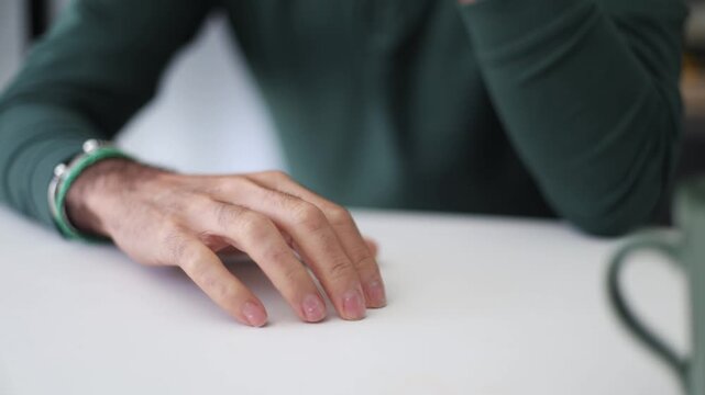 Nervous man drumming fingers on white table