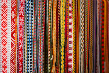 Close-up of colorful handwoven traditional belts displayed in a basket, highlighting their intricate patterns and vibrant colors.