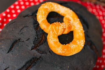 Traditional dark bread loaves topped with golden baked pretzels, displayed on a red polka-dot cloth.