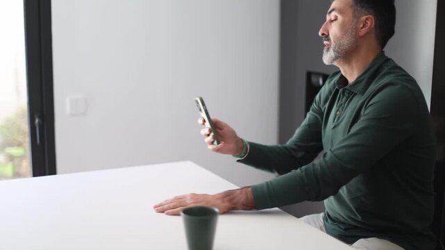 Mature man using smartphone gets startled and jumps backwards