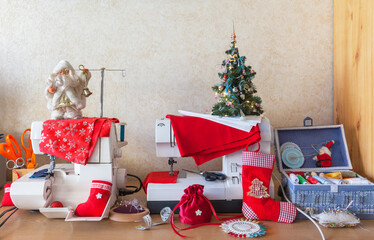 Merry Christmas and Happy New Year! Getting ready for the holidays. Sewing gifts, gift bags, and holiday stockings. Christmas tree and Santa Claus toy on sewing machines. Winter needlework concept