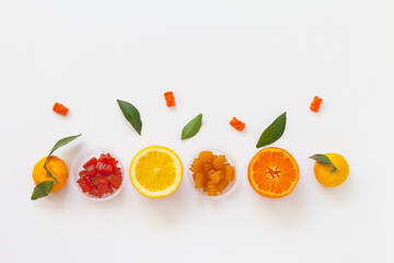 Flat lay of row children's gummy bear vitamins and ​natural ​citrus fruits on white background. Empty space for text, blank, prescription. Boosting immunity in winter. Top view, close-up, copy space