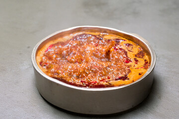 A pot of spicy Chinese hot pot soup base boiling on an induction stove. Red chili oil and steam highlight its intense flavor and heat.