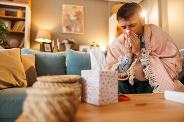 Sick man having flu coughing, sneezing and blowing nose using paper tissues