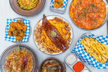 A fusion spread with grilled eel rice, pizza, fries, chicken, pasta, taco, and dipping sauces on a light table.