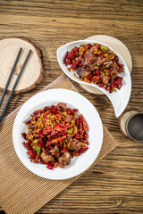 A spicy Chinese chicken dish with dried chilies, garlic, and green onions served on rustic plates.