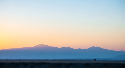 Fototapeta premium Serene Mountain Range Silhouette at Sunset with Soft Pastel Sky