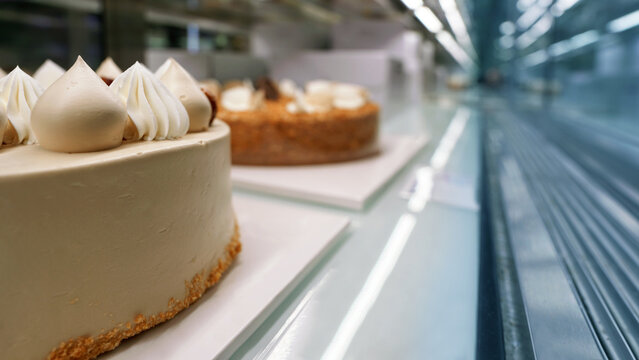 Variety of fresh cakes displayed in bakery refrigerator showcase - Powered by Adobe