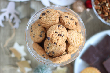 Various Christmas decorations, cookies, chocolate and nuts on wooden background. Flat lay.