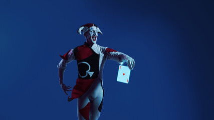 Jester presenting glowing ace card in vivid blue light. Concept of gaming promotions, entertainment visuals, digital casino themes, and playful character branding infused with excited energy.