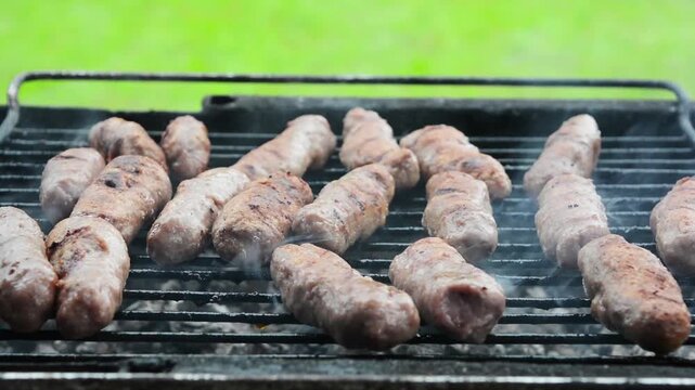 Grilled cevapi on barbecue grill with smoke
