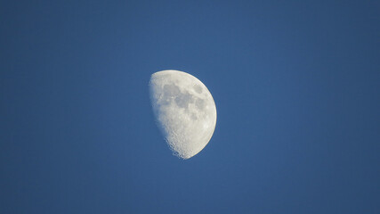 Zoom view of the moon and craters in high definition, silhouetted against the sunset sky