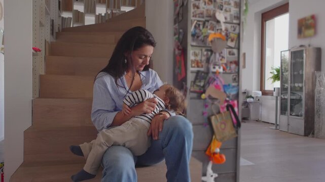 Mother breastfeeding sleeping toddler on wooden stairs creating calm intimate moment filled with tenderness steady presence and gentle care inside bright quiet corner of warm family home - Powered by Adobe