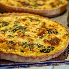 Freshly baked spinach and cheese quiche with a golden, flaky pastry crust. Perfect for bakery, brunch, recipe, and food-service usage, showcases texture, melted cheese pockets and visible spinach