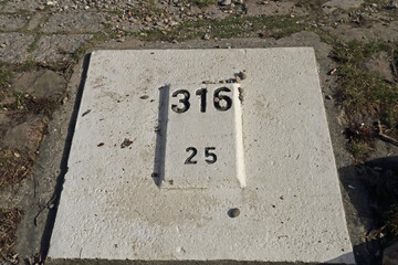 Kilometerstein am Flussufer