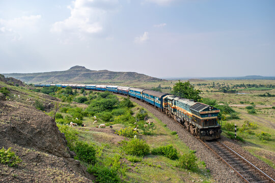 A passenger train is passing over a curve through a scenic section on Pune-Miraj railway line