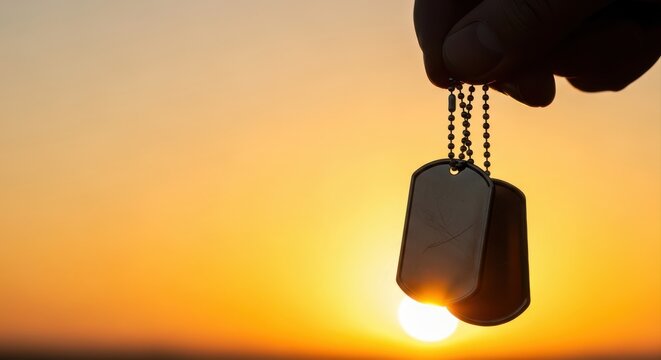 Military dog tags held at sunset in tribute
