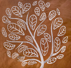 Close up of brown fabric with tree and leaves shape pattern sewn in white color thread. Suitable for upholstery, pillow accents, and drapery. Seamless background texture.