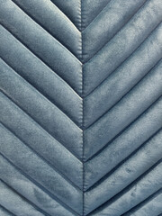 Close up of fabric in chevron pattern, in baby blue color. Chevron pattern upholstered panel in pale blue suede fabric. Seamless background texture.